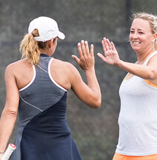 Two women high fiving in tennis attire