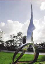 Abstract sculpture in grass area next to sidewalk