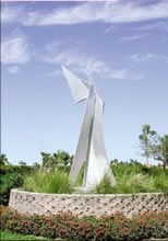 Abstract statue in brush area with brick-lined center where statue stands